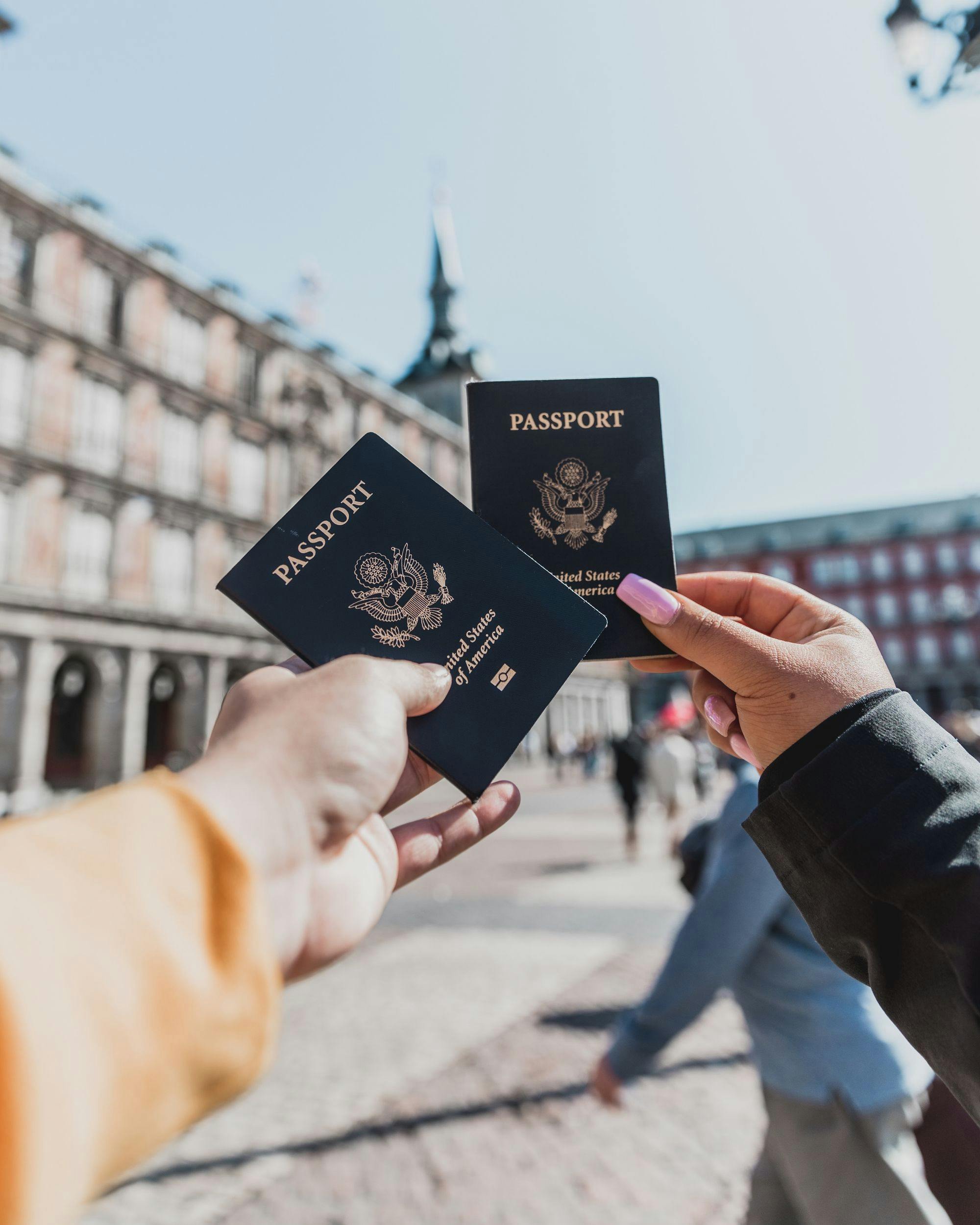 two-hands-holiding-passports-in-european-town-people-in-background
